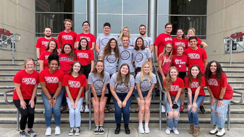 A group of students pose for a photo on the steps outside Memorial Stadium