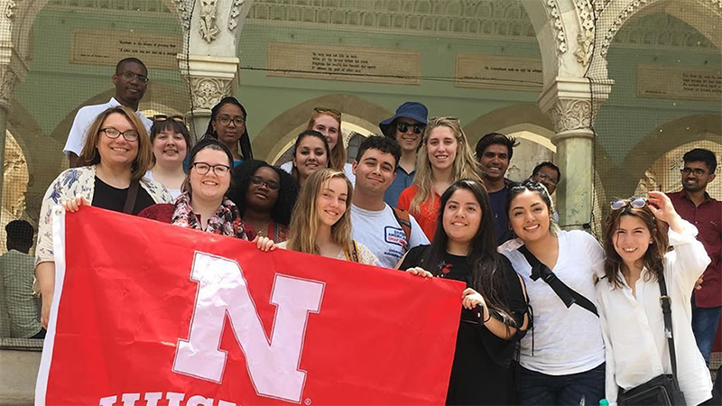 Students holding a red flag with a Nebraska N logo.