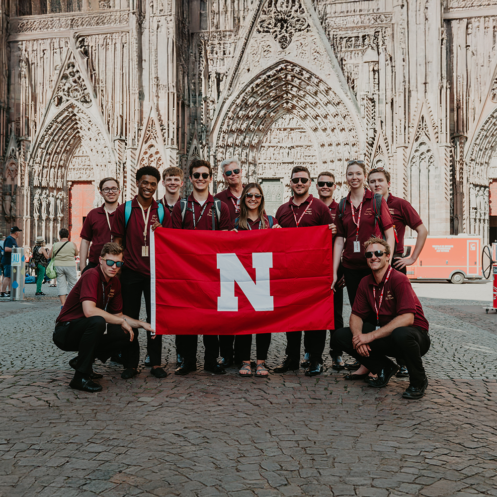 Students holding a red flag with a Nebraska N logo.