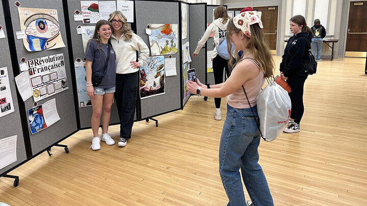 Students representing Lincoln East in the poster contest pose for a picture next to their entry.